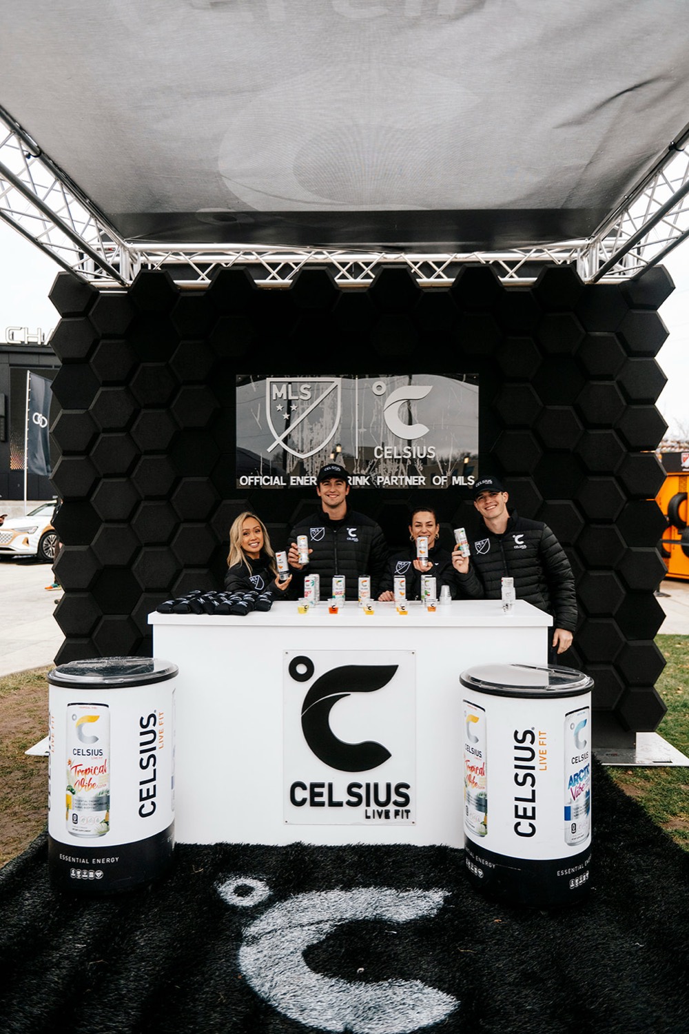 Celsius brand ambassadors sampling product at the branded bar in front of the MLS partnership wall